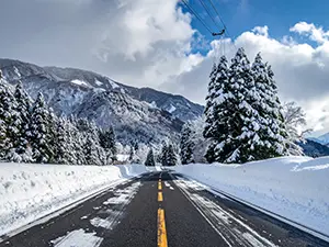 青空の下、両脇に雪が積もった綺麗に除雪された直線道路
